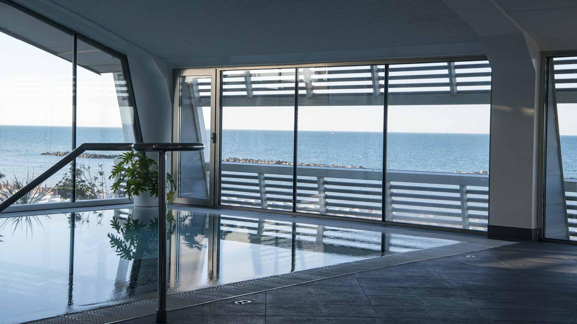 Piscina interna con vista mare, atmosfera rilassante e moderna.